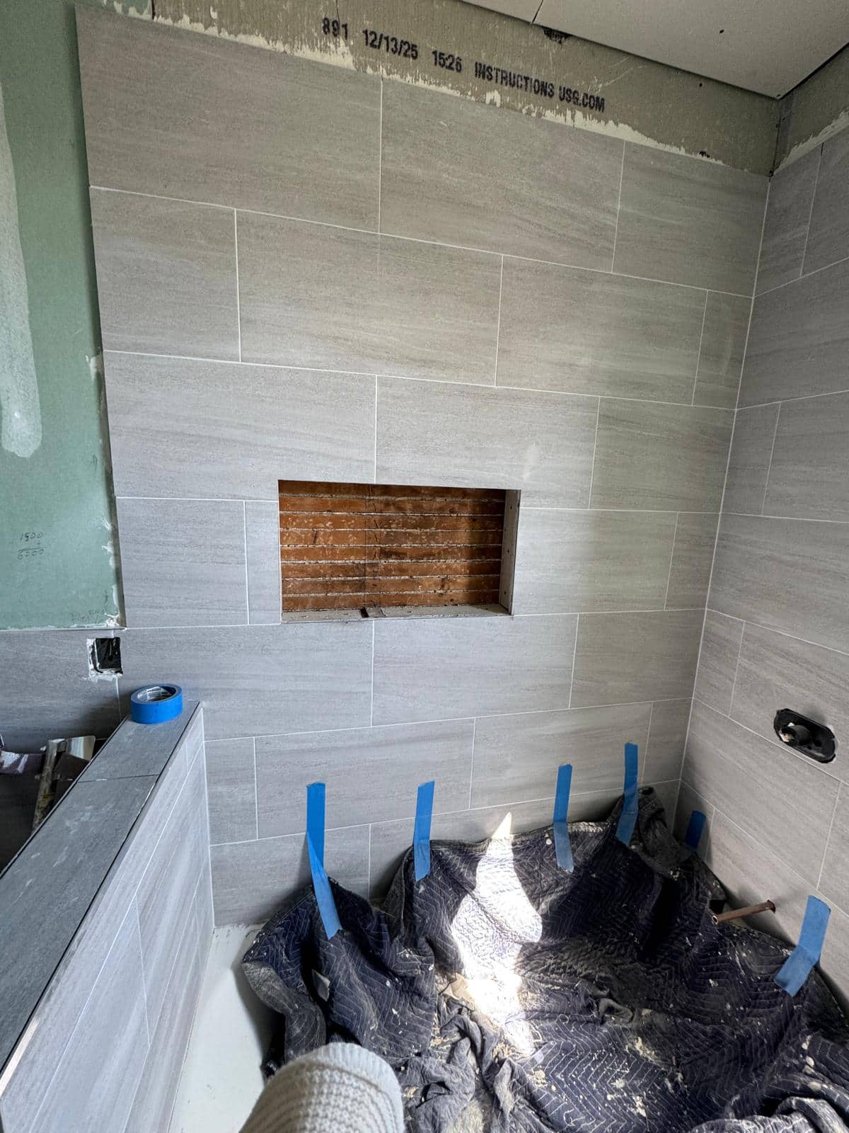 The gray tub surround appears here at a stage before all fixtures and edge finishes are in place.