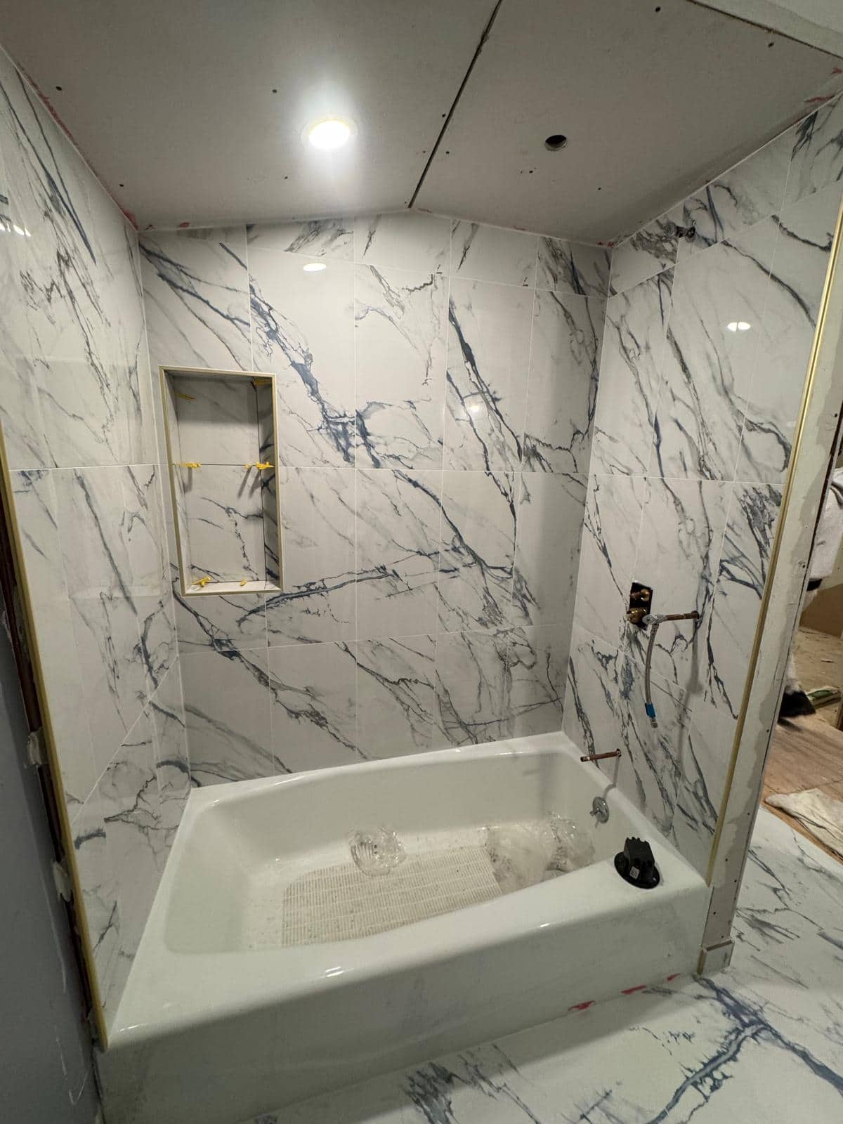 Marble-look tub surround with recessed niche during remodeling.