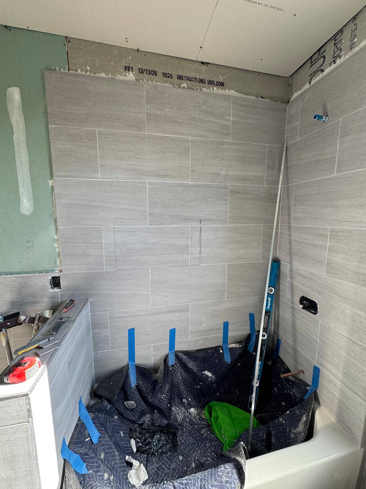 The gray horizontal tile is being built around a tub and recessed niche.