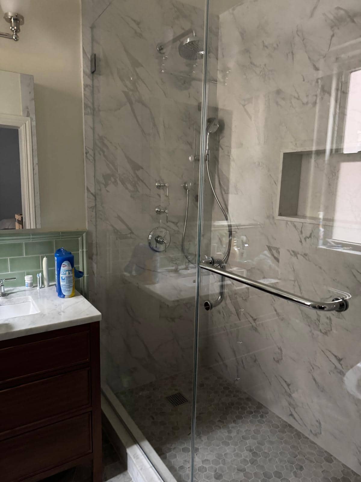 Finished shower enclosure with marble-look tile and glass partition.