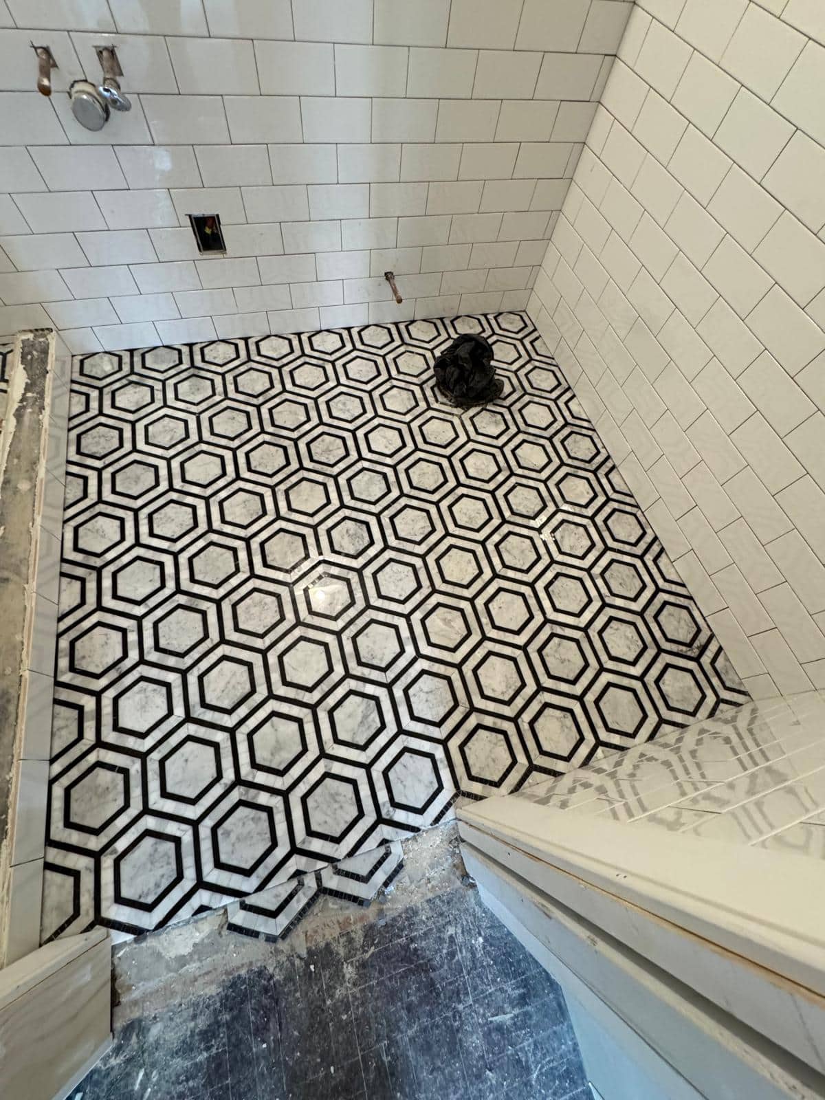 Black and white hex pieces cover a shower floor with the drain visible.