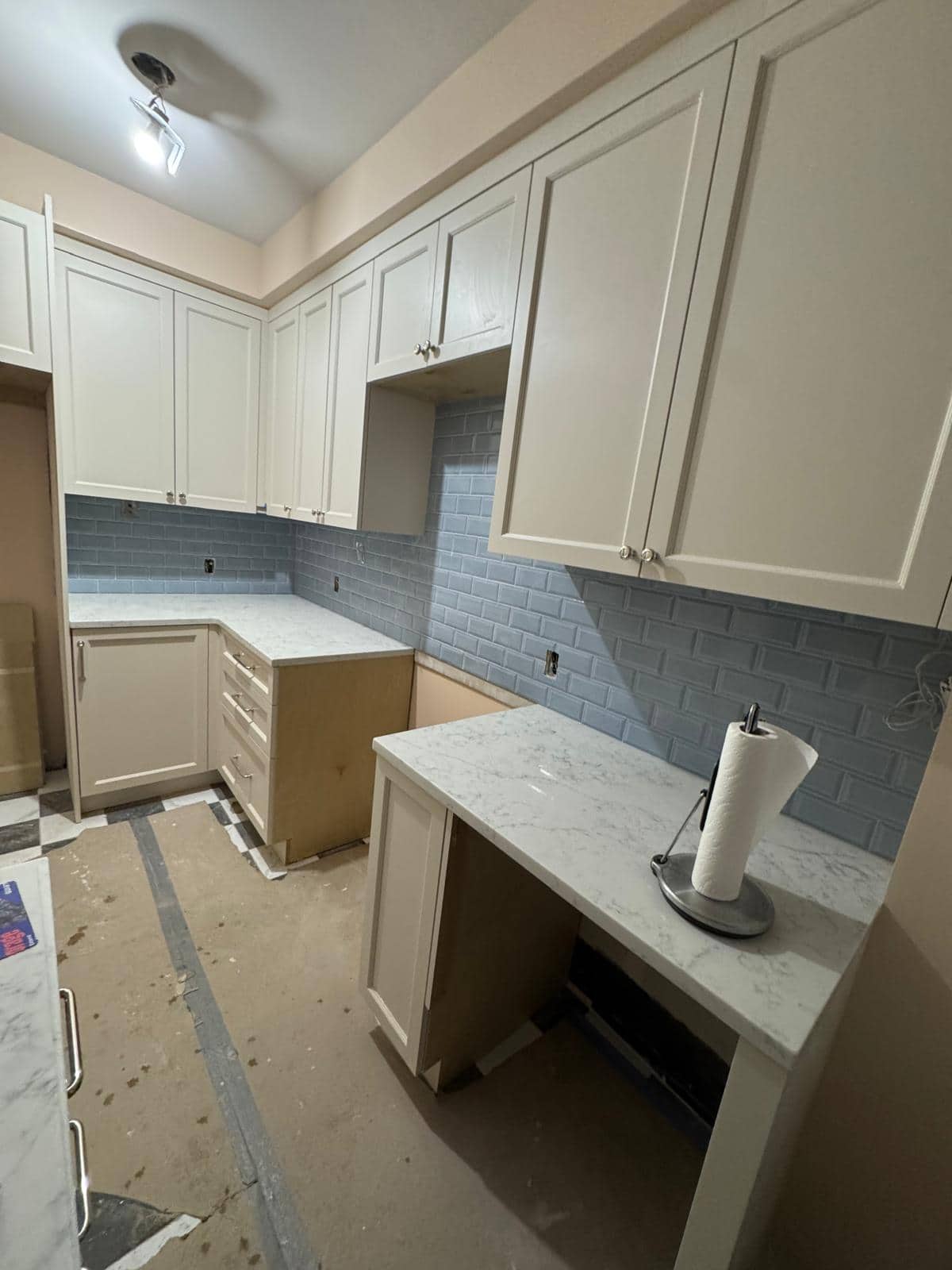 Cream cabinets and a blue backsplash are visible above a protected floor.