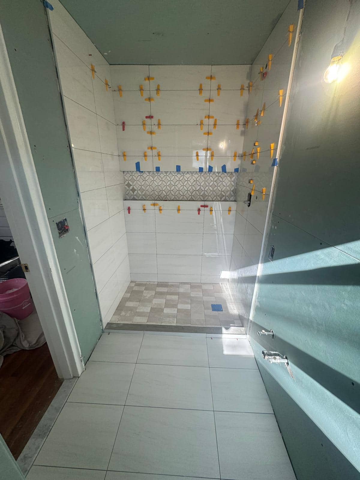 Most of this shower uses quiet white tile, while the niche introduces a small field of color.