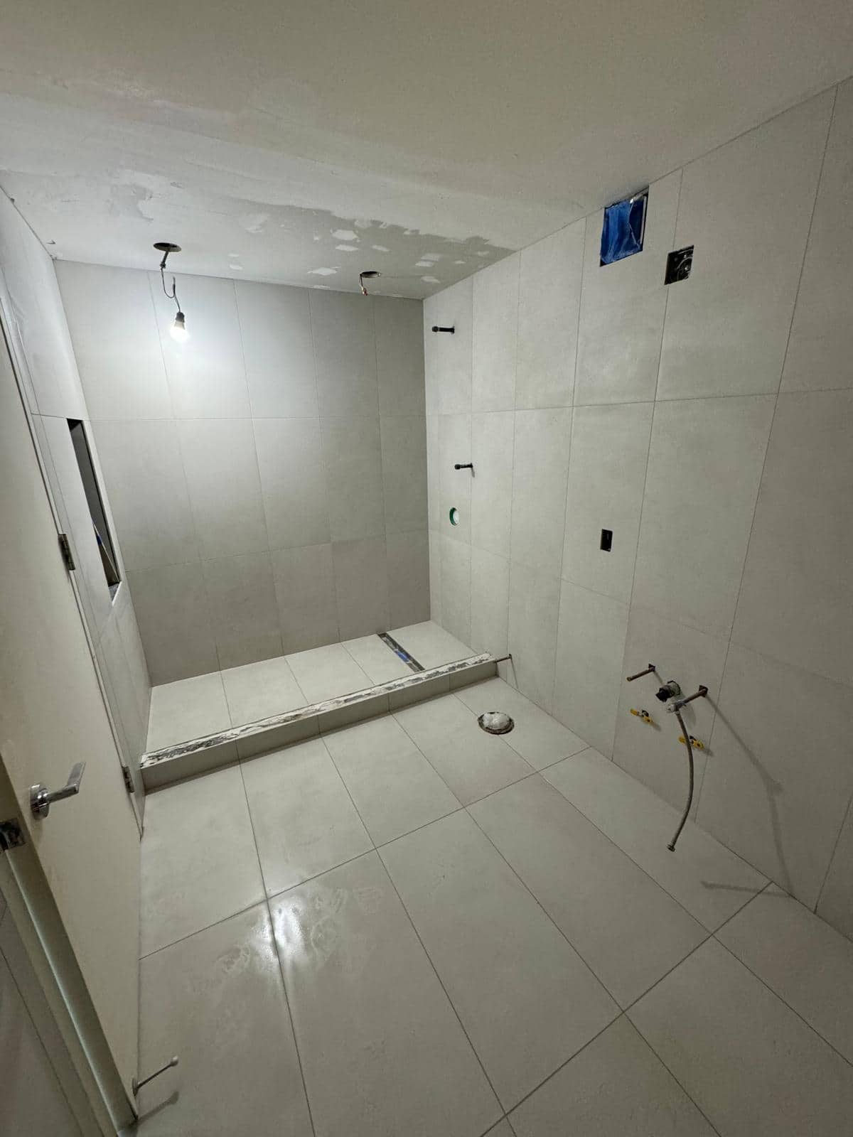 This angle shows the pale shower walls and floor together, with hardware still to come.