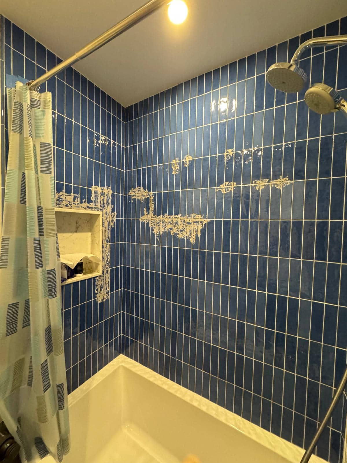 Deep blue vertical tile gives this tub wall its rhythm, but the light patches show that the wall was photographed during the work.