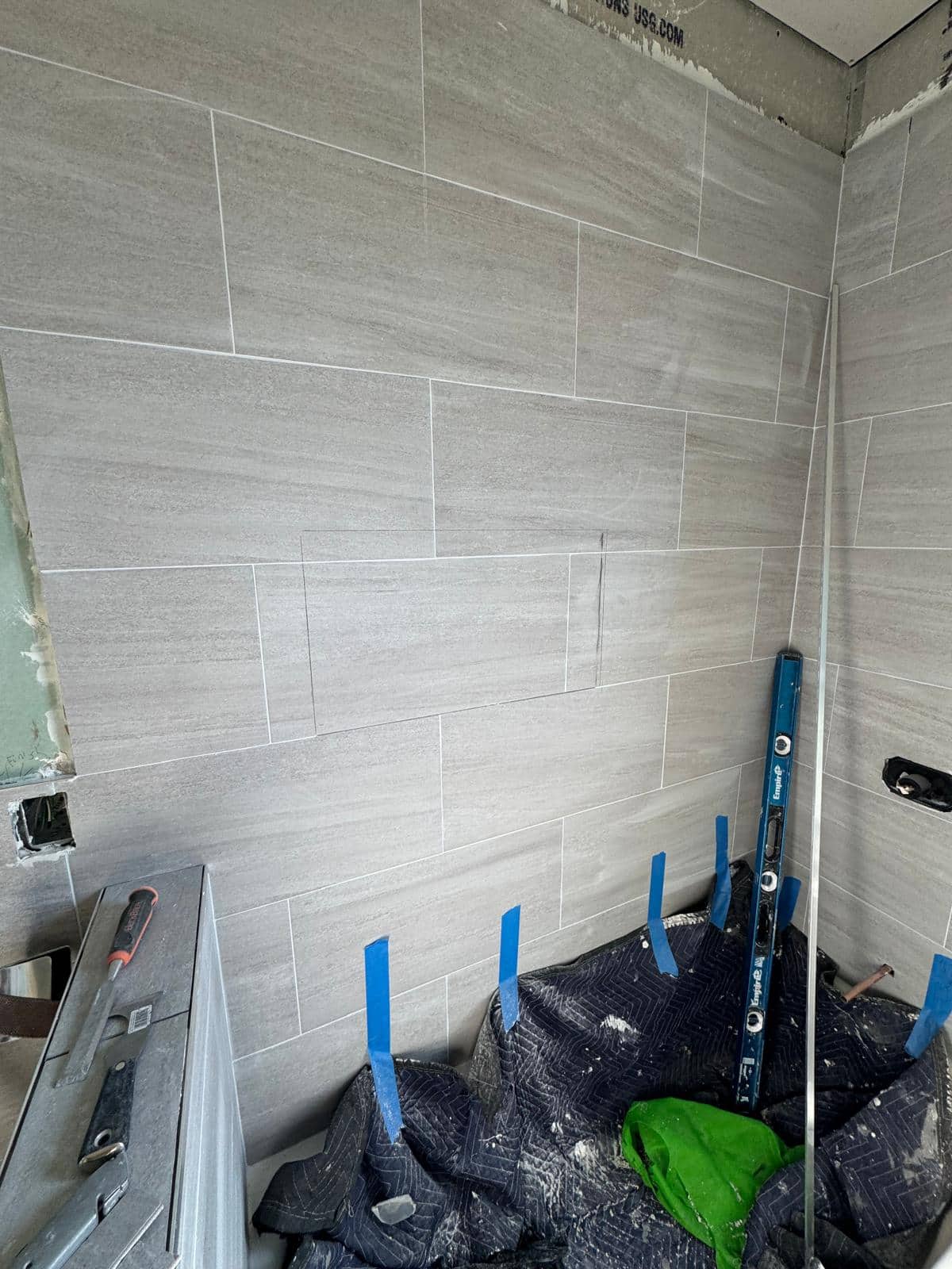 This closer view of a gray tub surround draws attention to the cuts around the recessed niche and the unfinished edge.