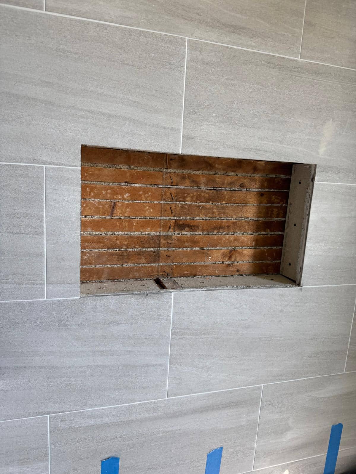 Gray tile surrounds a recessed niche whose interior is still open in this photograph.